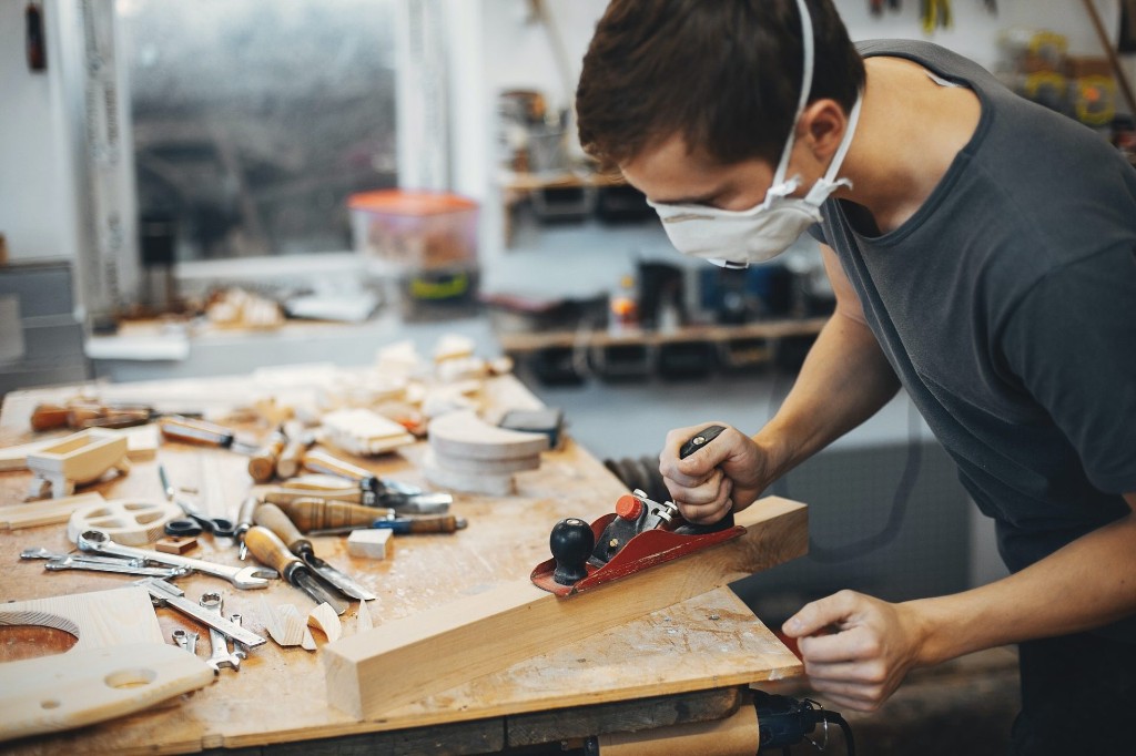 Carpenter planing timber by hand in the workshop