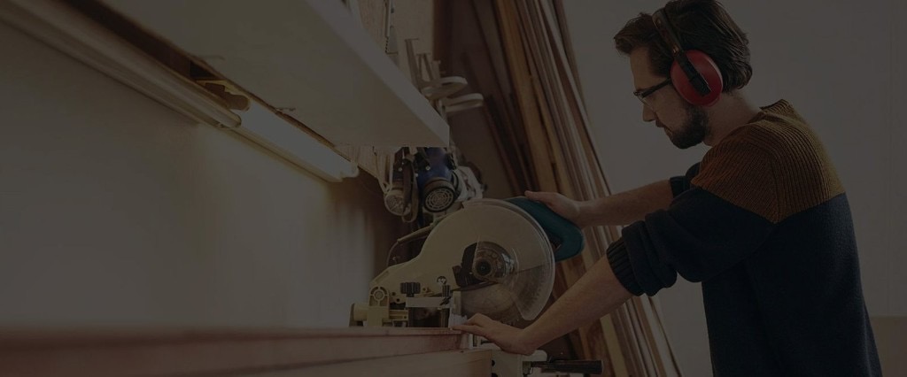 Craftsman cutting lumber with a miter saw in the workshop