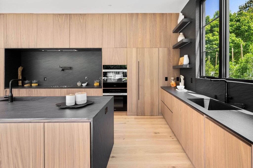 Modern kitchen with light wood cabinetry and dark stone surfaces